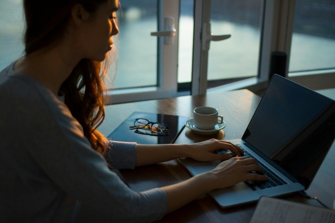 Person arbejder ved en bærbar computer med en kaffekop ved siden af